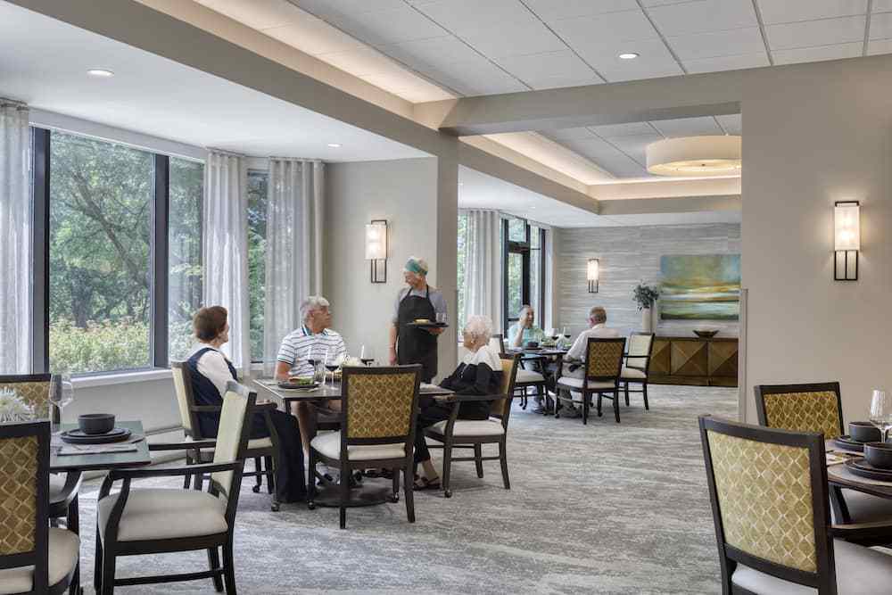 A spacious dining area with seniors enjoying a meal at various tables.