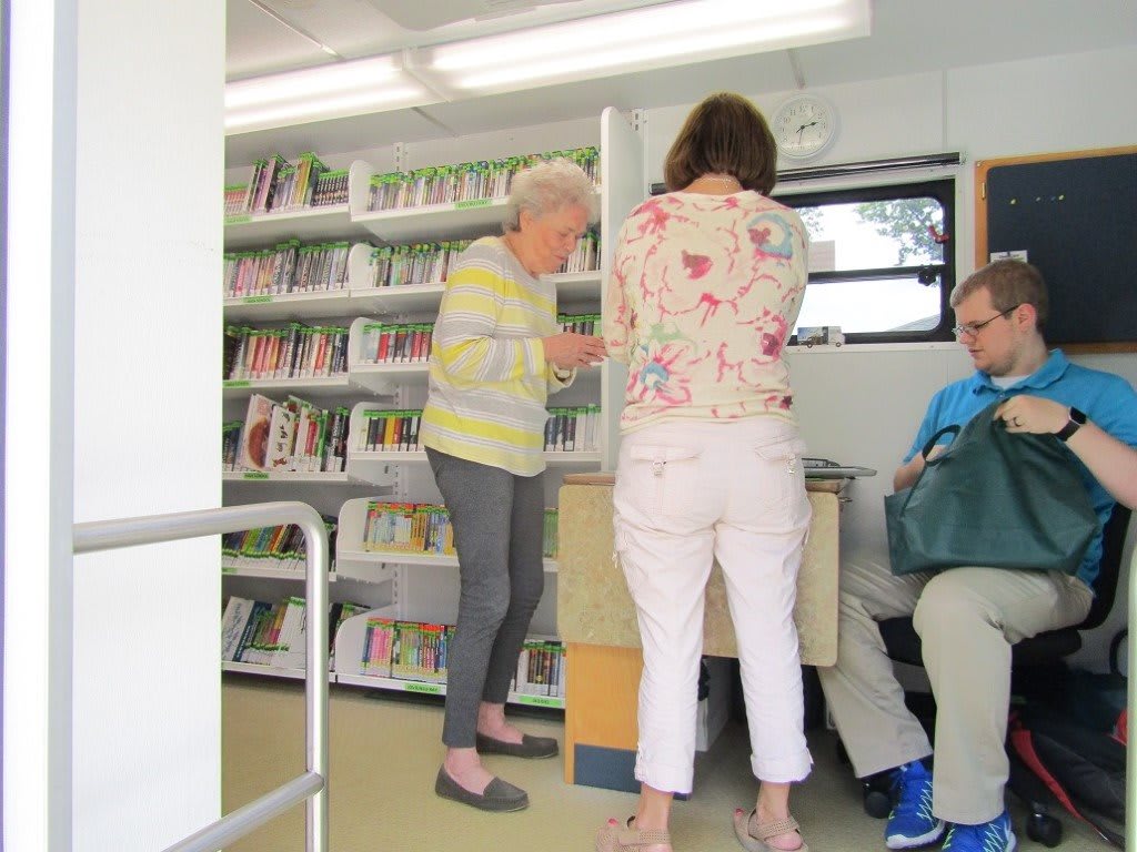 A group of people inside a mobile library browsing books.