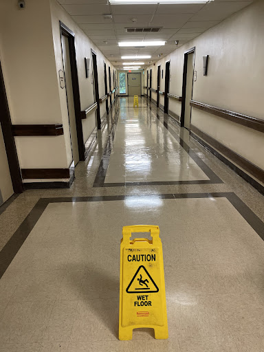 A hallway in a hospital with a caution sign warning of a slippery floor.