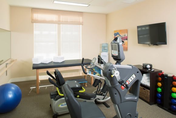A fitness room with various exercise machines and a large window.