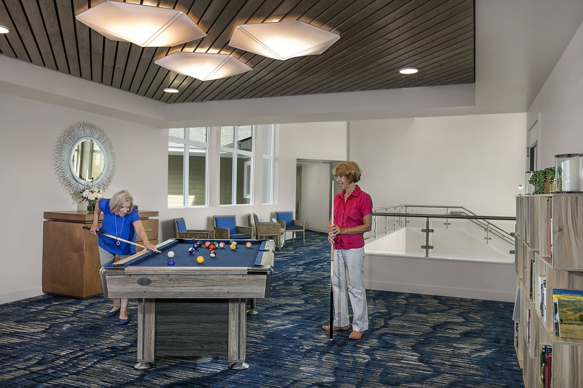 Two people enjoying a game of pool in a recreation room.