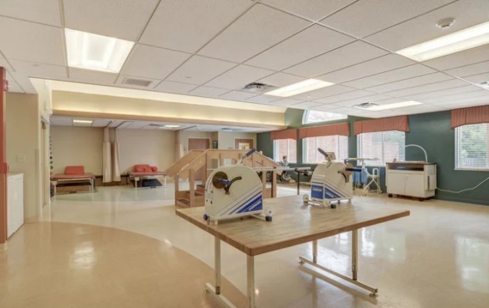 An indoor rehabilitation center with exercise equipment and spacious layout.