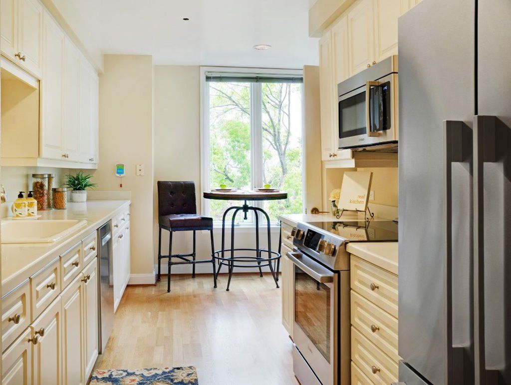 A modern kitchen interior with stainless steel appliances and a cozy dining area by the window.