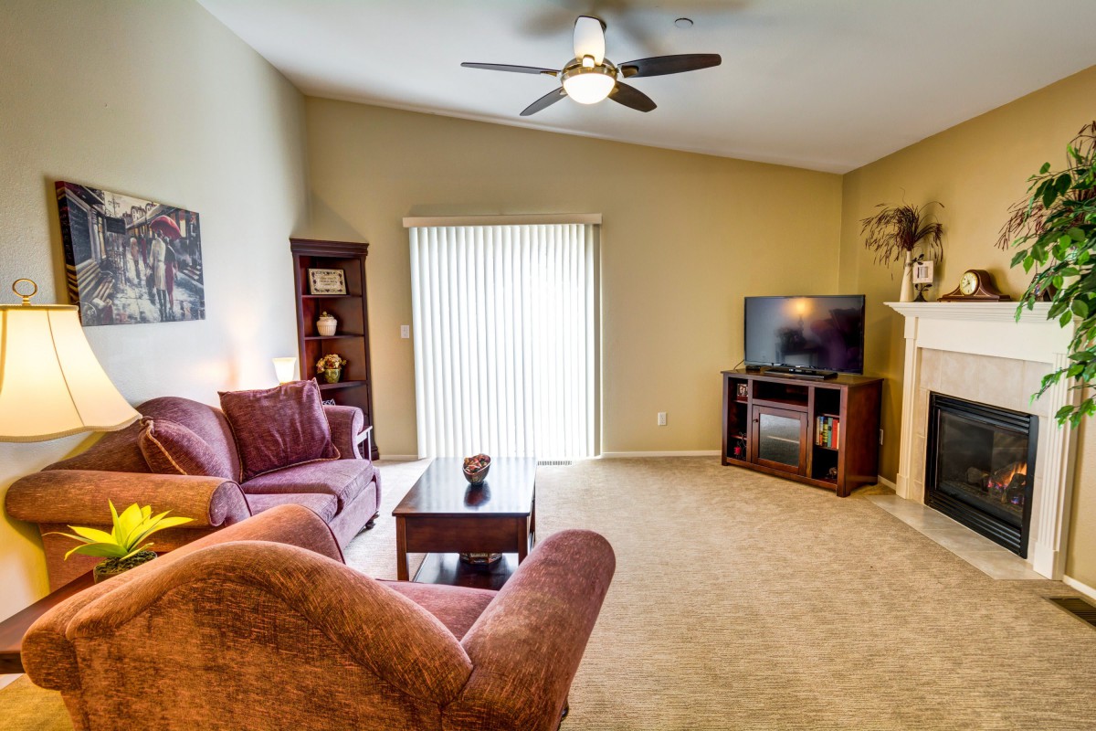 A cozy living room featuring a plush sofa, TV, and bookshelf with soft lighting and neutral decor.
