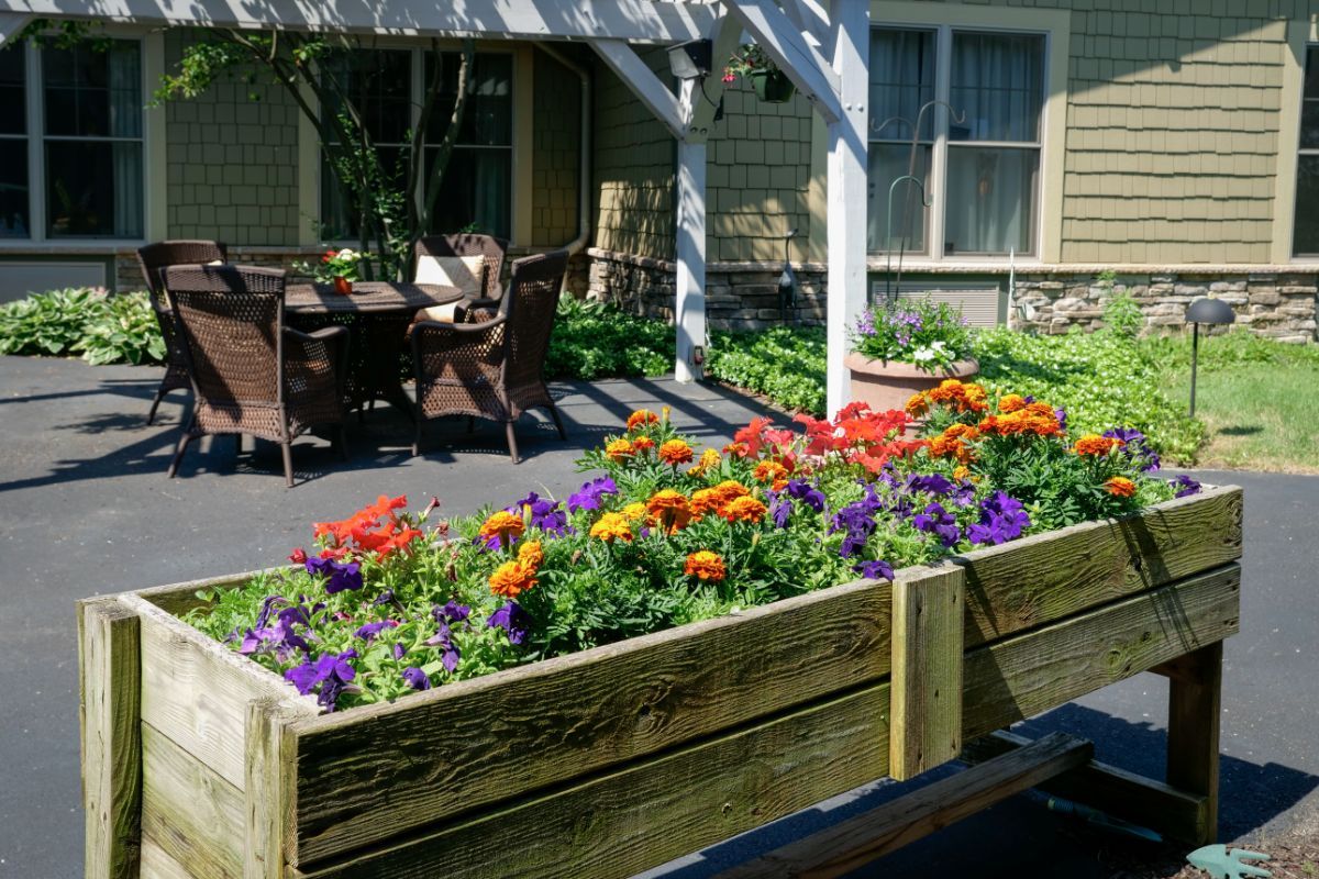 A beautiful garden with a raised flower bed and outdoor seating on a patio.