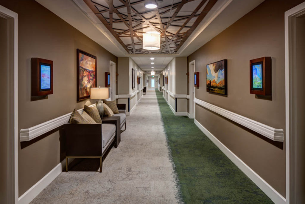 A modern hallway with artwork and a seating area.