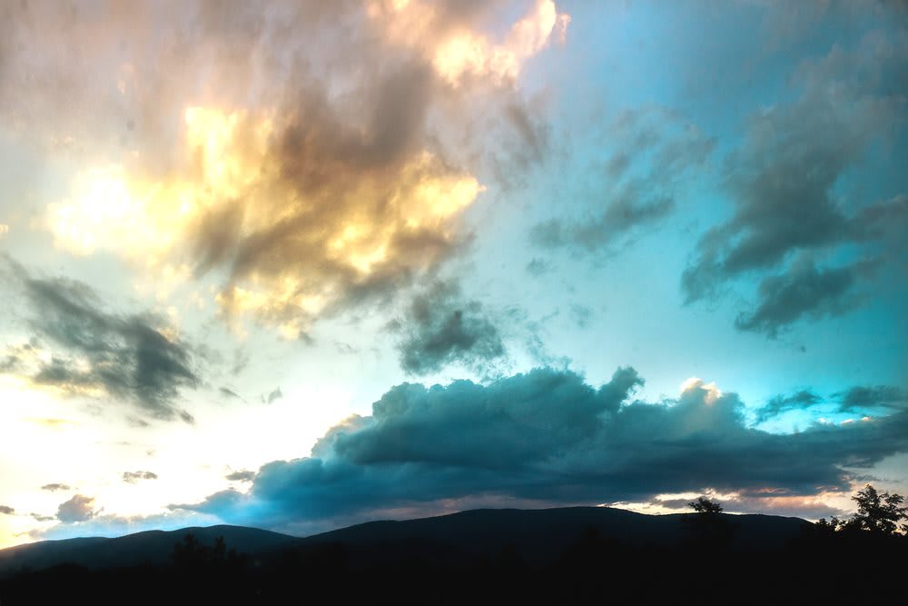 A stunning sunset with vibrant clouds over a silhouetted landscape.
