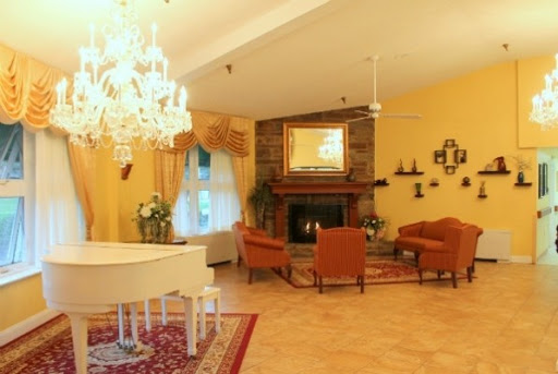 A warm and inviting living room featuring a grand piano, elegant chandelier, and cozy seating area.