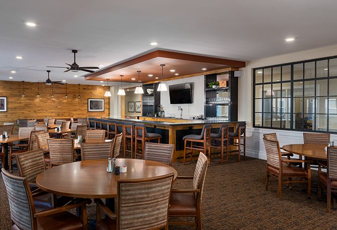 A cozy restaurant interior with wooden furniture and a bar area.