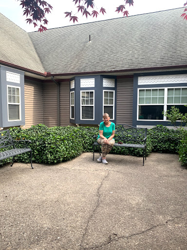 A person sitting on a bench in a garden area outside a building.