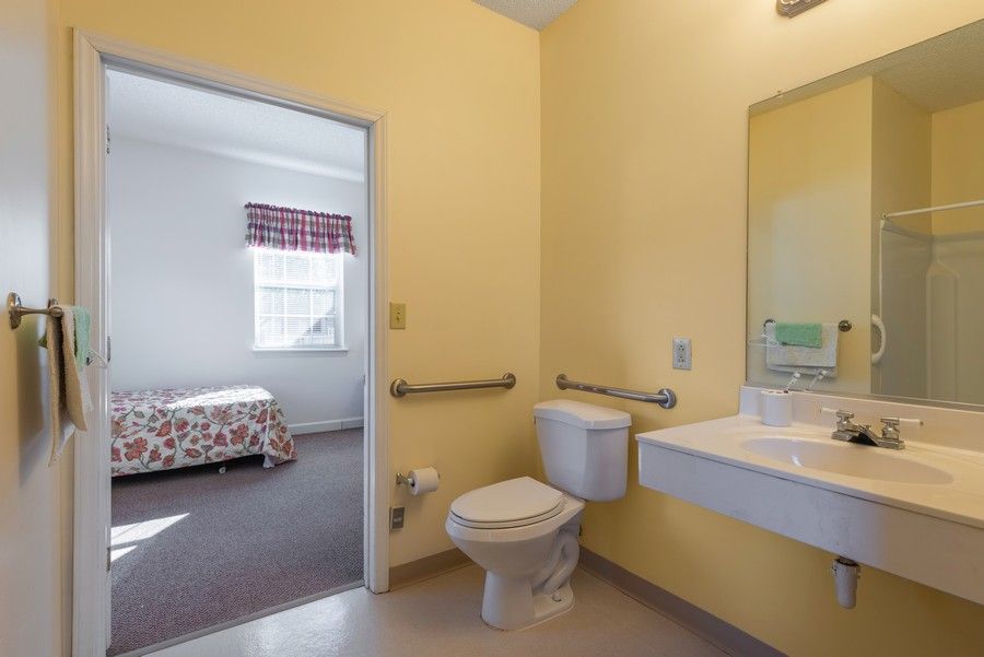 An accessible bathroom in a hotel room with a view into the bedroom.