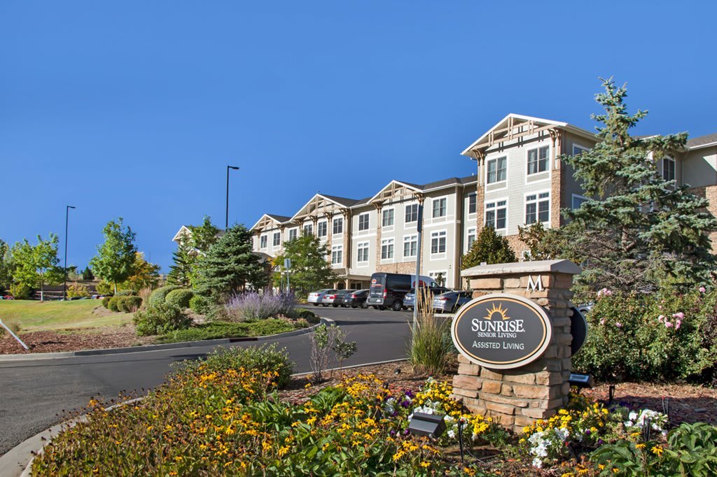 A large residential building with landscaped gardens and a clear blue sky.