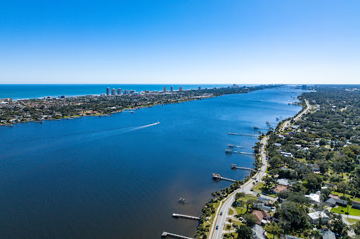 A stunning aerial view showcasing a tranquil river bordered by residential areas and a vibrant city skyline in the distance.