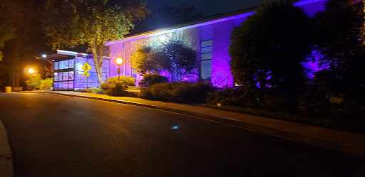 A building illuminated with vibrant purple and blue lights at night, creating a striking visual effect.