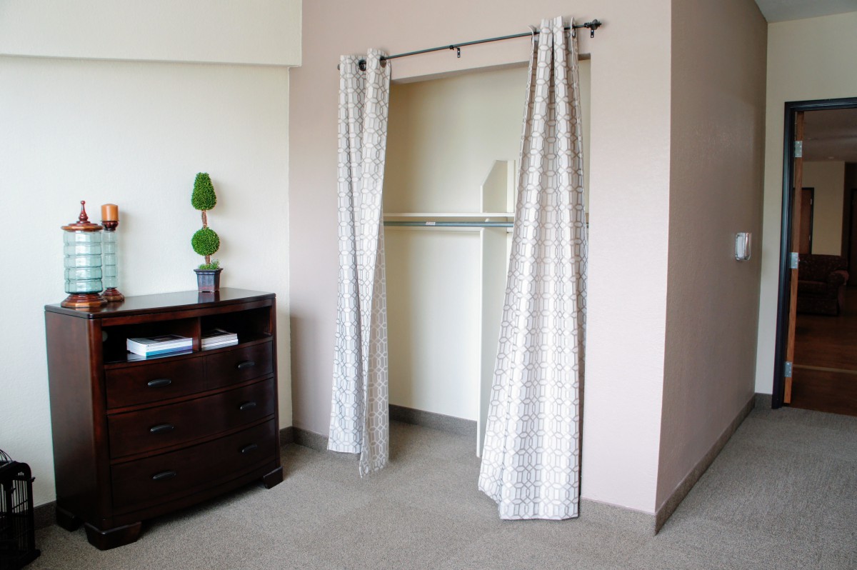 A minimalist bedroom with an open closet featuring curtains as a door alternative.