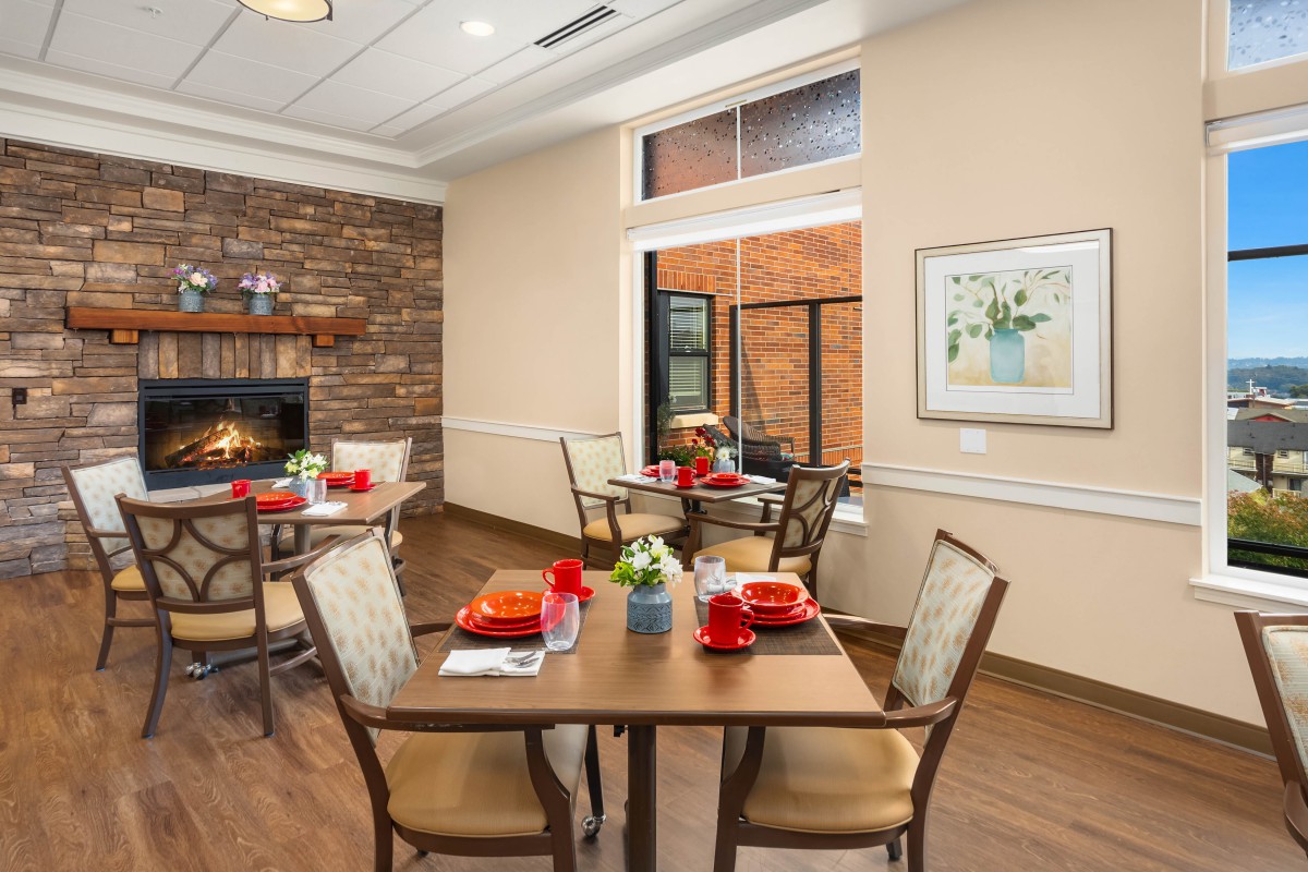 A cozy dining room with neatly set tables and a fireplace.