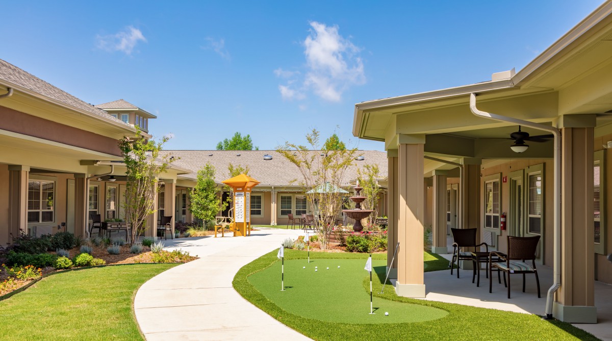 A tranquil courtyard with a winding pathway and well-maintained garden on a sunny day.