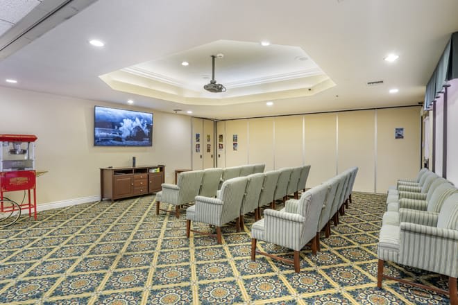 An interior view of a conference room with rows of seating and a projector screen.