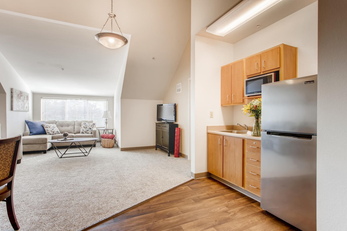A modern apartment with an open floor plan, featuring a cozy living room and a compact kitchen area.