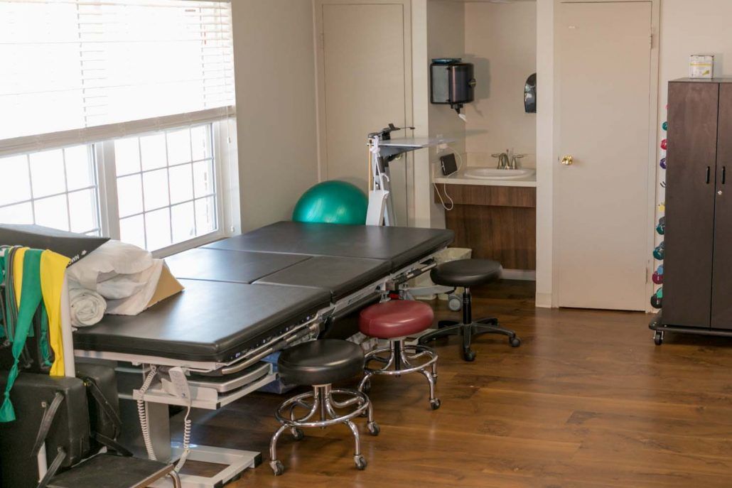 A medical office with a treatment table, exercise ball, and stools.