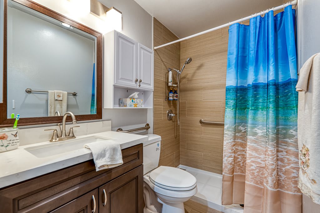 A well-organized bathroom with a beach-themed shower curtain and modern fixtures.