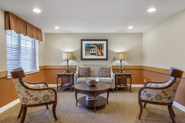 A cozy living room with a sofa, chairs, coffee table, and artwork on the wall.