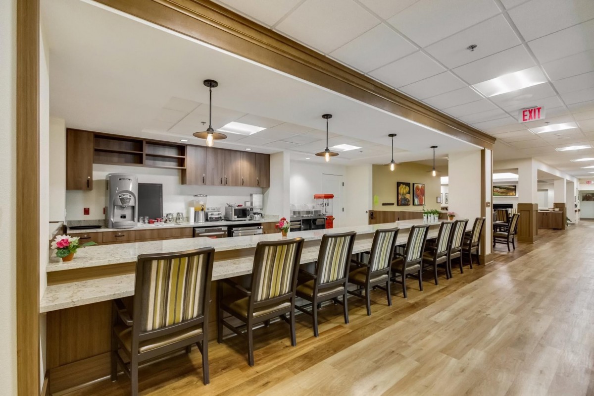 Modern kitchen area with a long counter and bar stools.