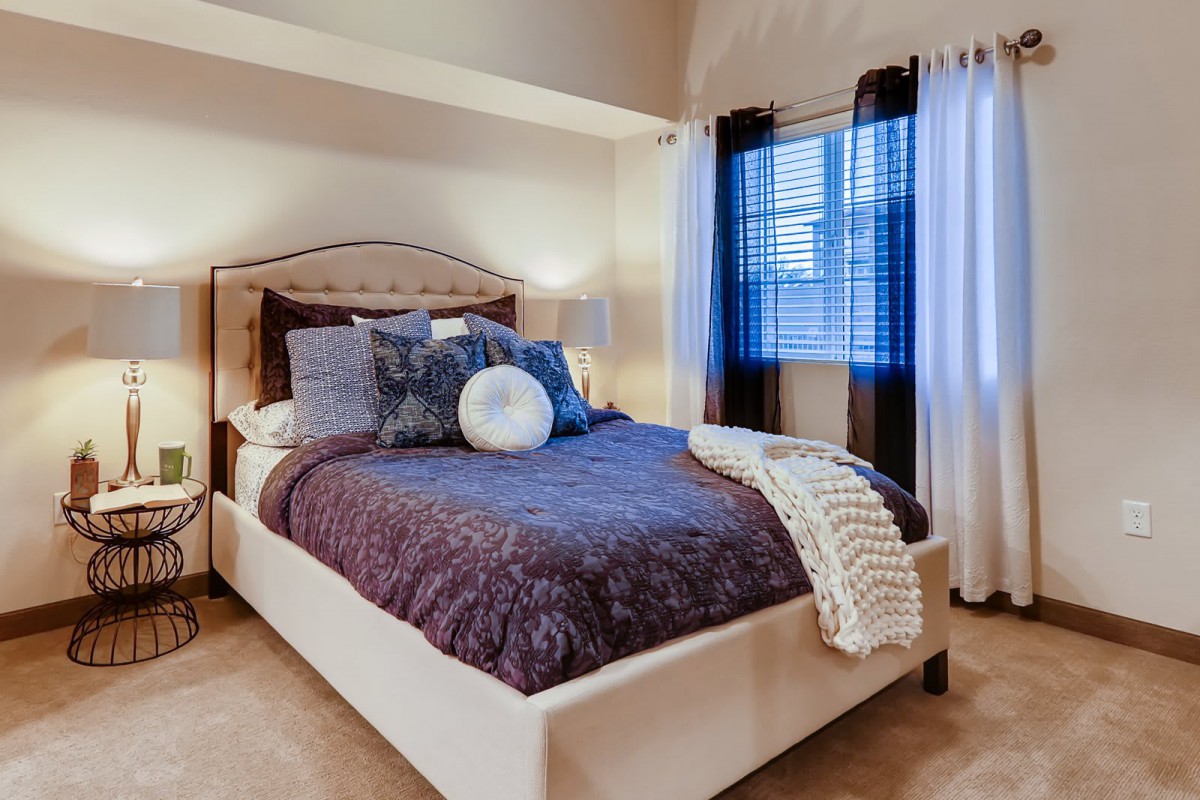 A cozy bedroom with a neatly made bed, featuring multiple pillows and a soft blanket.