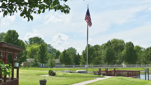 A serene view of a U.S. flag proudly flying amidst a park setting, surrounded by lush greenery.