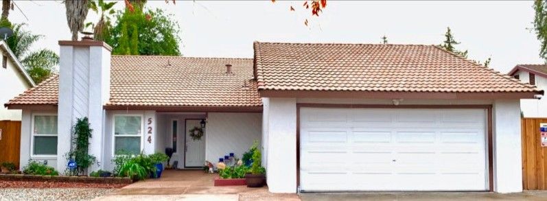 A residential house featuring a tiled roof and a white garage door.