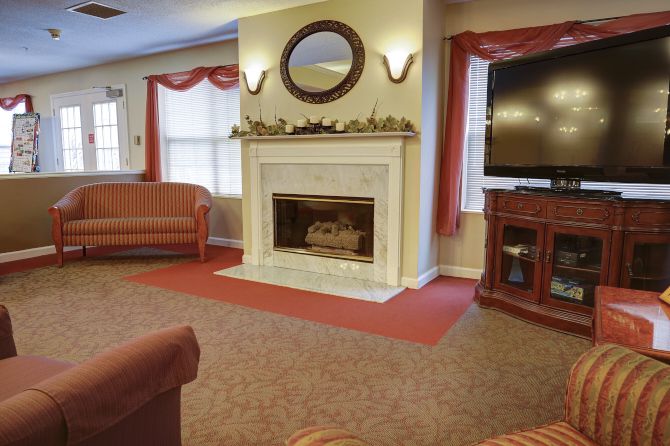 A cozy living room featuring a central fireplace, comfortable seating, and a television.