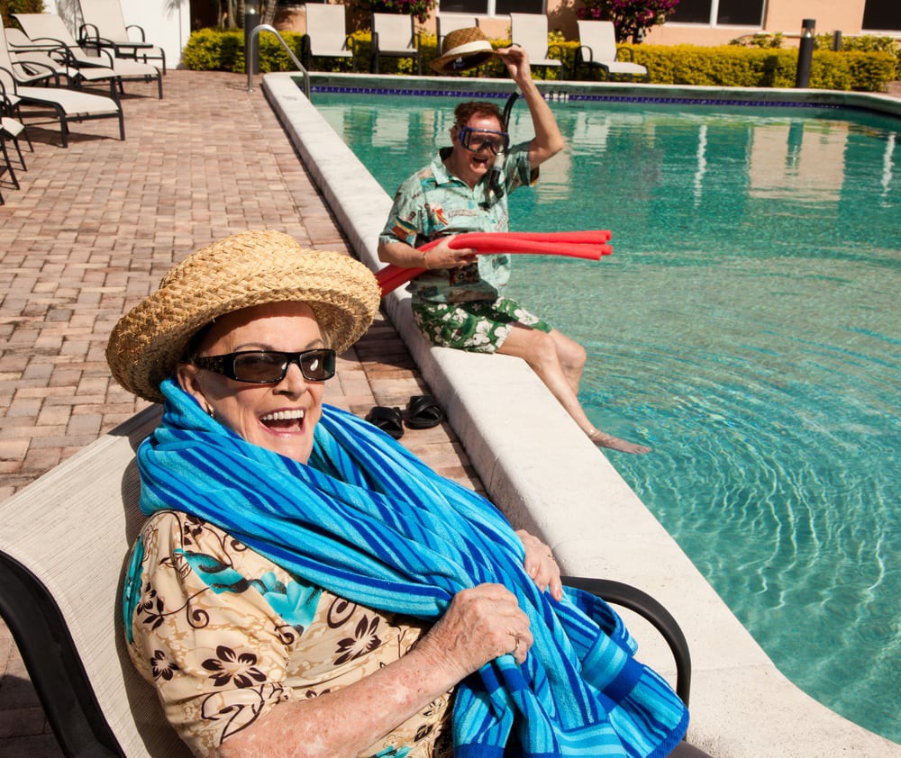 Elderly individuals enjoying a sunny day by the pool, dressed for fun and relaxation.