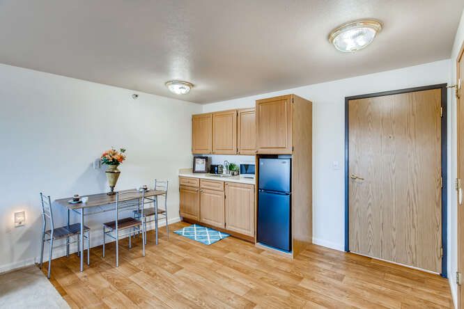 A modern kitchen with a dining table and wooden flooring in a compact living space.