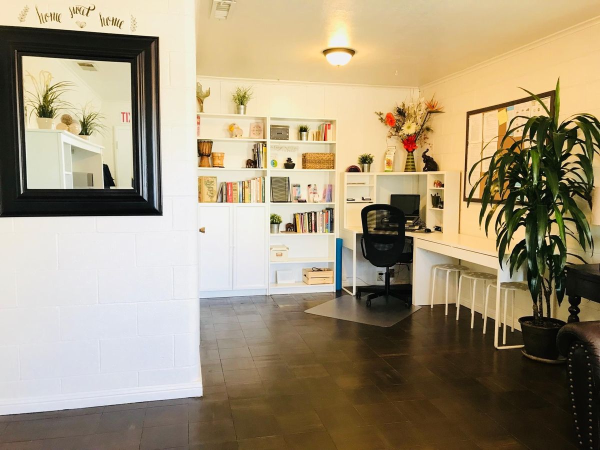 A clean and organized home office with a large bookshelf, desk, and plants.