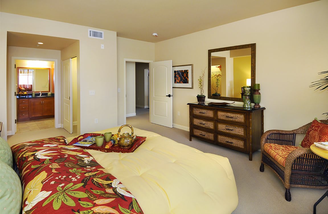 A well-decorated bedroom with a bed, dresser, and mirror.