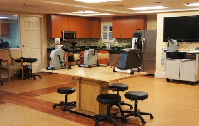 A multifunctional therapy room with kitchen facilities and exercise equipment.