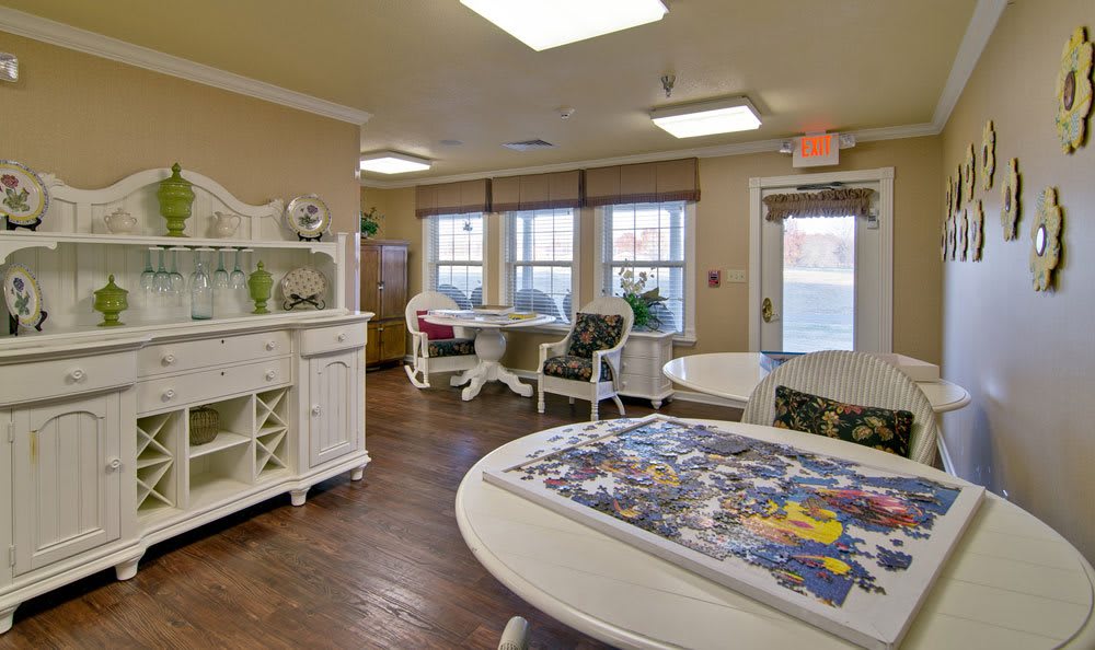 A cozy indoor room with tables and chairs, featuring a partially completed puzzle on one table.