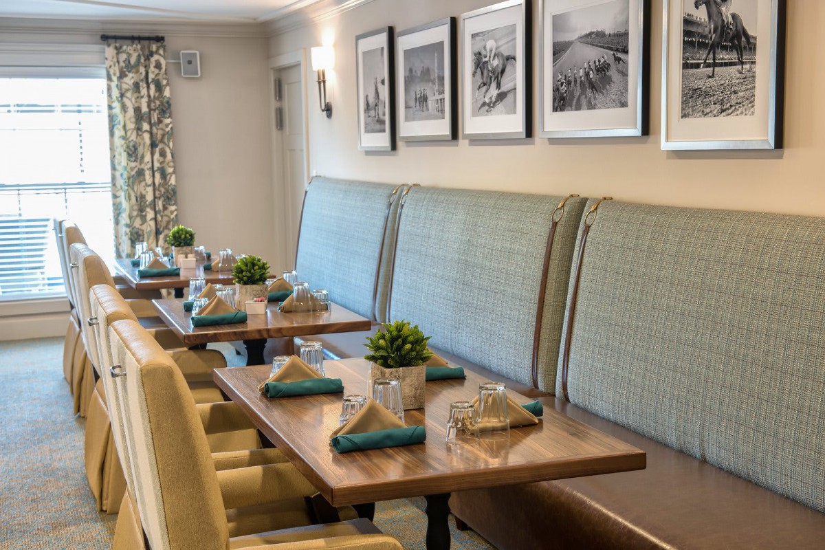 A cozy restaurant interior with neatly set tables and upholstered seating.