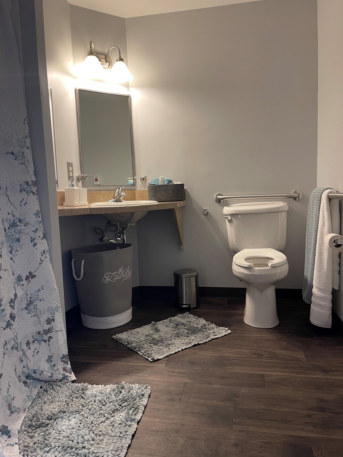 A clean and modern bathroom with a toilet, sink, and mirror next to a shower area.