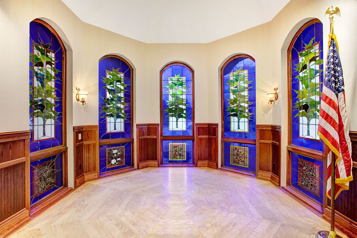 A beautifully designed room with stained glass arched windows and wood paneling.