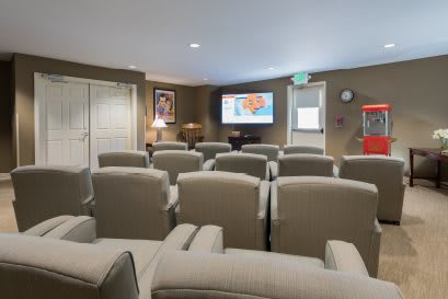 A cozy home theater with rows of comfortable seating facing a large screen.