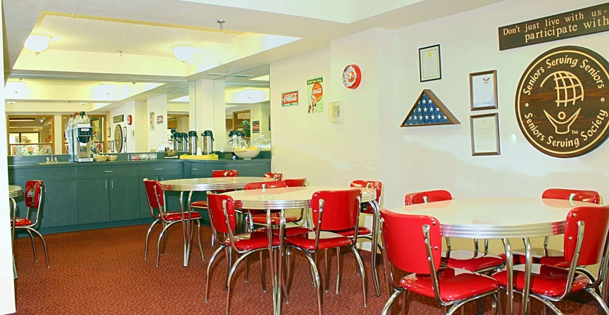 A retro-style diner with red chairs and tables, decorated with classic wall art.