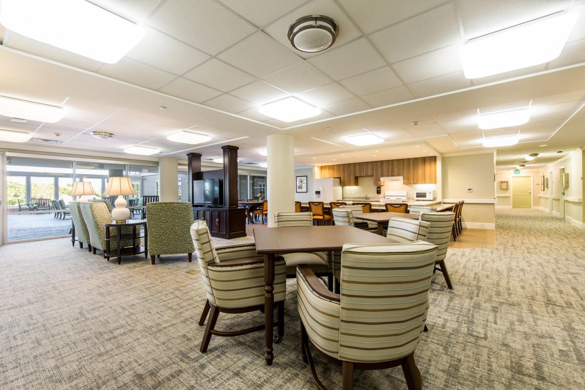 A spacious living area with comfortable seating and a kitchen in the background.