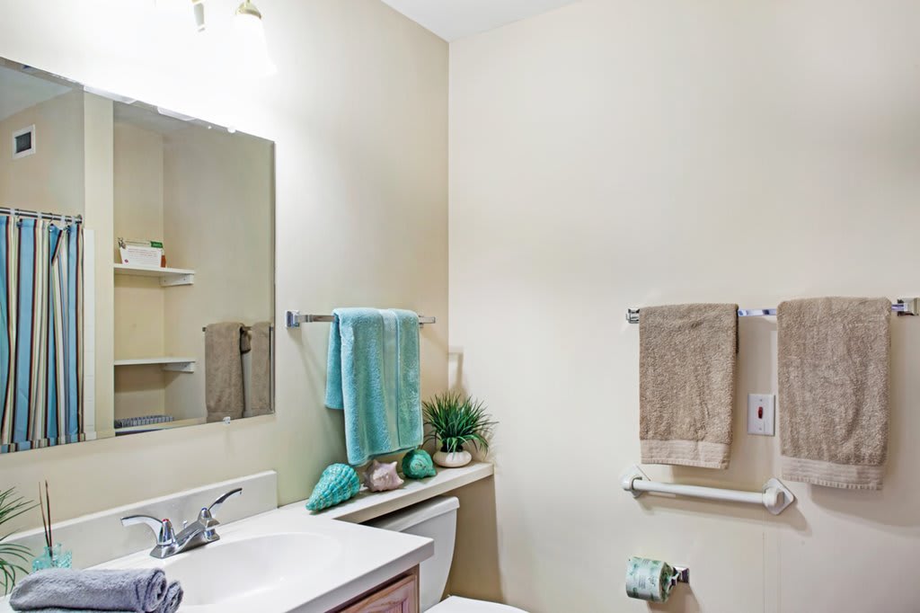 A neatly organized bathroom with a sink, mirror, and towel rack.