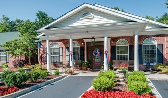 A well-maintained building with a landscaped entrance, featuring columns and patriotic decorations.