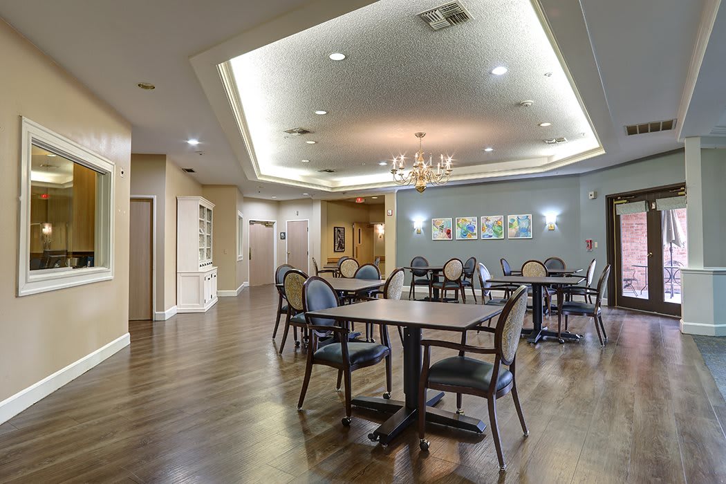 A spacious dining area with elegant tables and chairs, featuring polished wood flooring and ambient ceiling lighting.