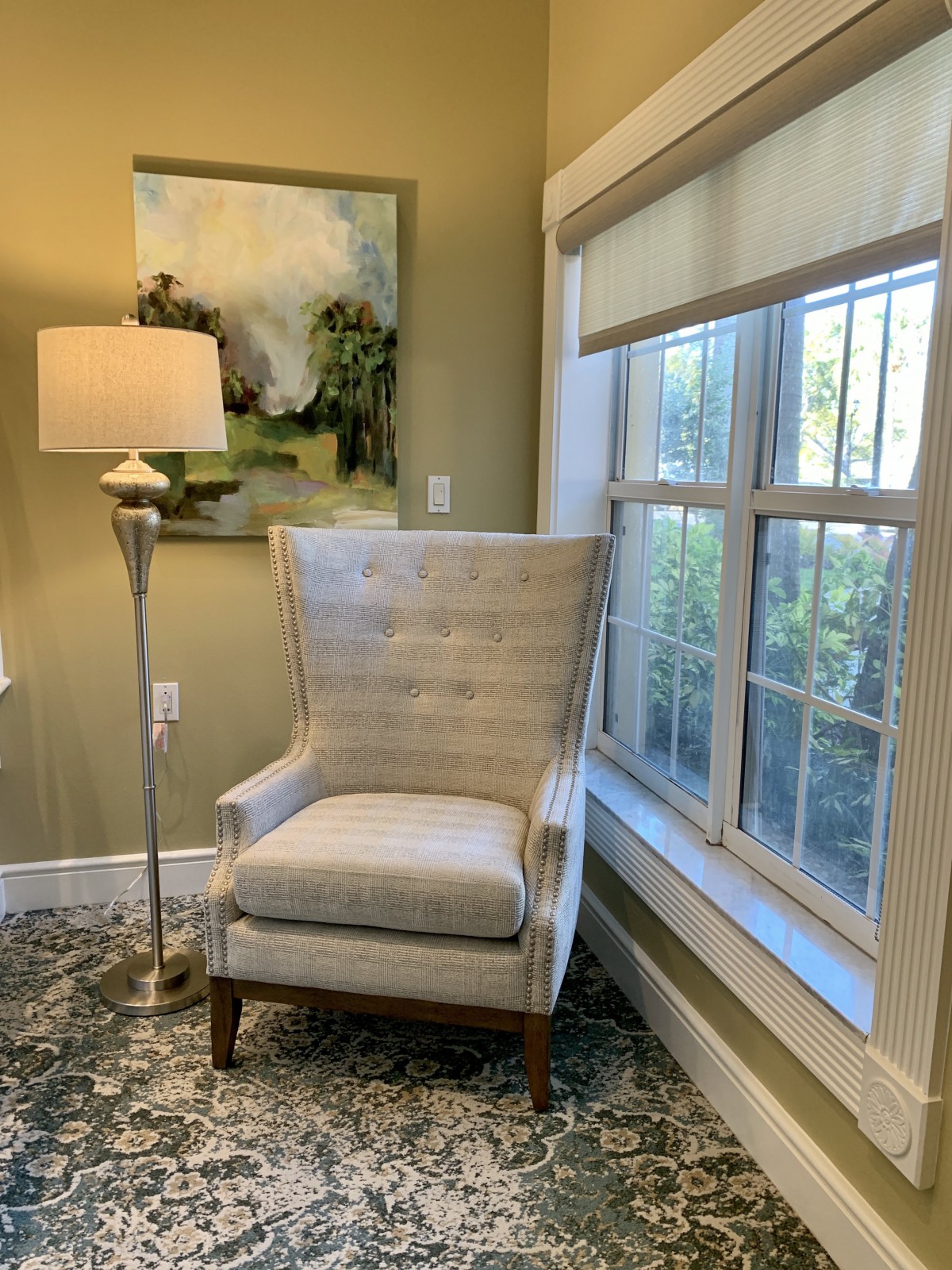 A cozy corner with a tufted armchair next to a floor lamp and window.