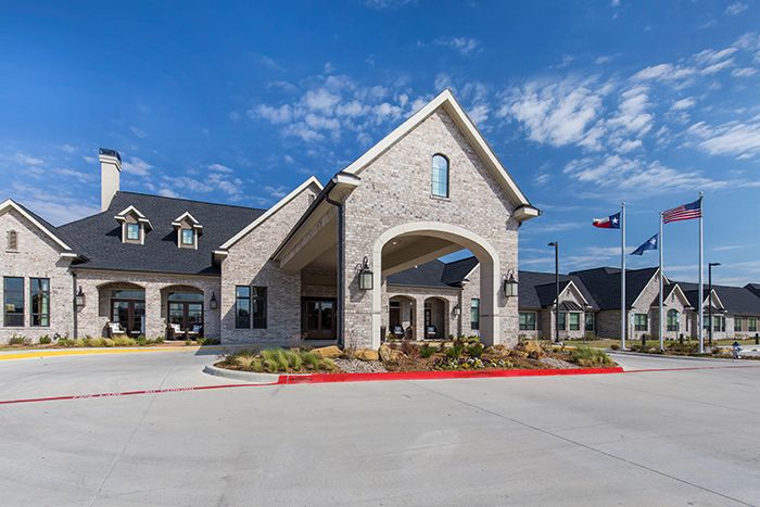 A modern residential building with a stone facade and an inviting entrance, set against a clear blue sky.
