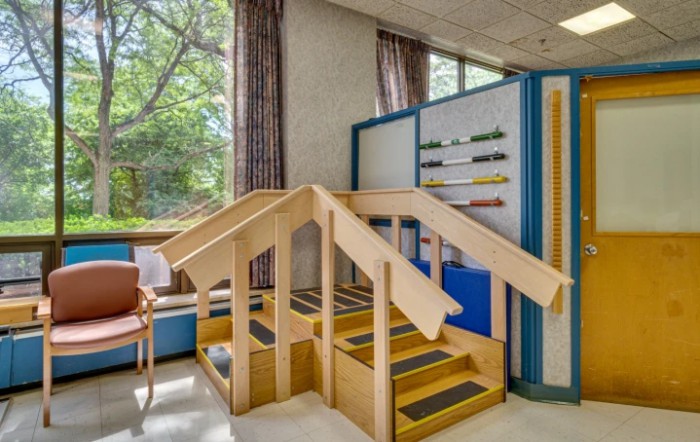 A physical therapy room featuring wooden stairs for rehabilitation exercises.