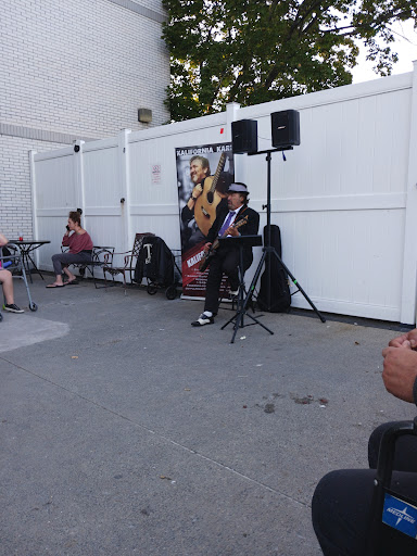A musician performing outdoors, entertaining a small crowd with live guitar music.